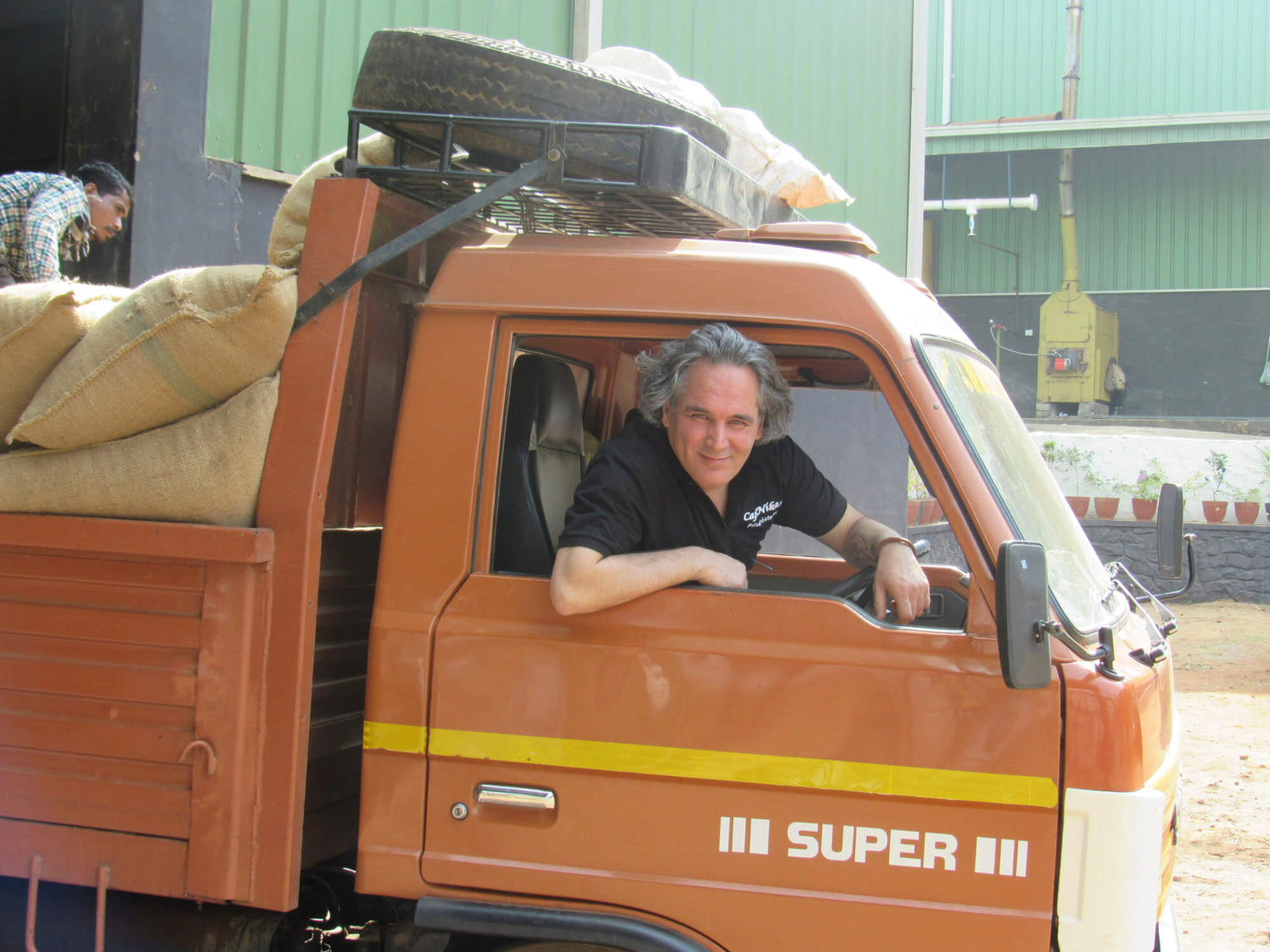 Kaffeebohnen werden in Kaffeesäcken von Farsin, dem Betreiber der Kaffeerösterei Nikan in einem orangenen Kleintransporter transportiert.